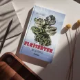 A képen az Elkísértek című könyv látható a háttérben egy kutyával.