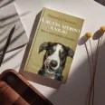 A kutya szerint a világ című könyv látható a képen a háttérben kutyákkal és macskákkal.