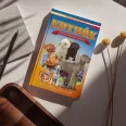 A képen a Kutyák képes ismeretterjesztés gyerekeknek című könyv látható a háttérben két kutyával.