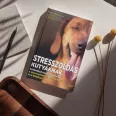 A képen a Stresszoldás kutyáknak című könyv látható erdei háttér előtt.