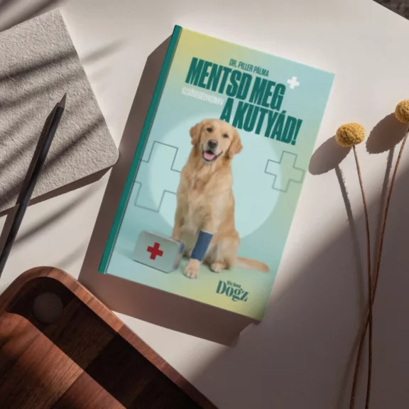 A képen a Mentsd meg a kutyád! - Elsősegélykönyv című könyv látható a háttérben egy kutyával.