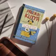 A képen a Pálcikakutya című könyv látható egy keverék kutyával a háttérben.