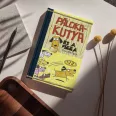 A képen a Pálcikakutya és a pizza című könyv látható a háttérben pizzákkal és kutyákkal.