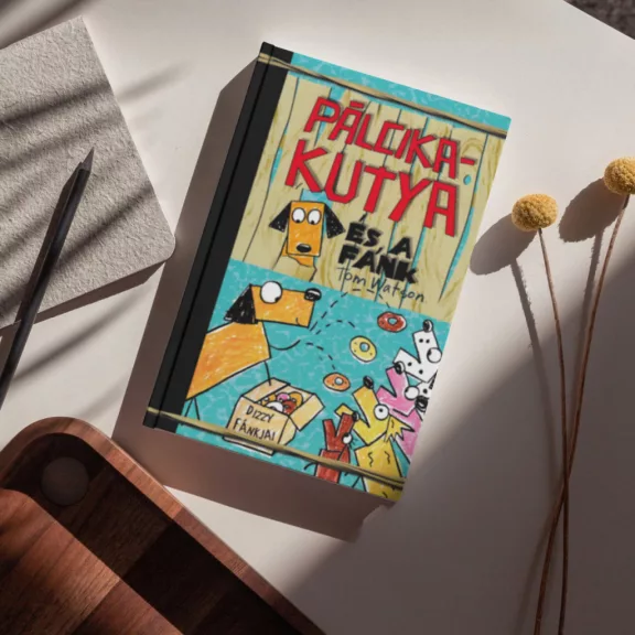 A képen a Pálcikakutya és a fánk című könyv látható a háttérben fánkokkal.