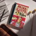 A képen a Pálcikakutya és a spagetti című könyv látható a háttérben spagettiból készült kutyákkal.