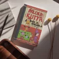 A képen a Pálcikakutya és a cukorka című könyv látható a háttérben cukorkákkal.