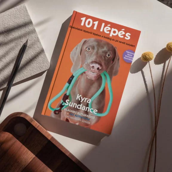 A képen a 101 lépés című könyv látható a háttérben egy vizsla.