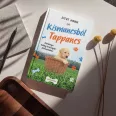 A képen a Kismancsból Tappancs című könyv látható a háttérben növényekkel és mancs nyomokkal.