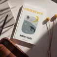 A képen az Egyszer egy kutya című könyv látható a háttérben egy fekete kutya.