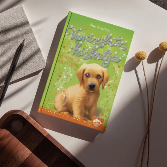 A képen a Varázslatos kiskutya című könyv látható egy labradorral a háttérben.
