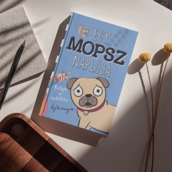 A képen az Egy mopsz naplója Kutya a rakétán című könyv látható a háttérben egy mopsz.