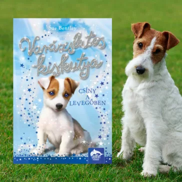A képen a Varázslatos kiskutya című könyv látható a háttérben egy foxterrier.