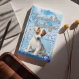 A képen a Varázslatos kiskutya című könyv látható a háttérben egy foxterrier.