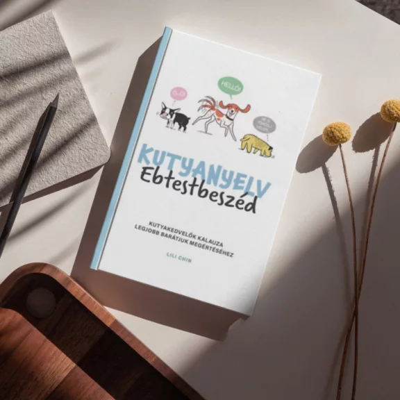 A Kutyanyelv Ebtestbeszéd című könyv látható a képen kutyákkal a háttérben.