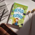 A képen a Neveld a kutyád című könyv látható a háttérben kutyáival játszó emberrel.