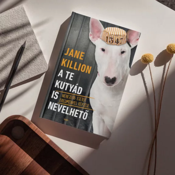 A képen az A te kutyád is nevelhető című könyv látható egy kutyával a háttérben.