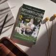 A képen a Kutyakötelesség című könyv látható a háttérben kutyákkal.