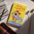 A képen A kiskutya aki szuperhős akart lenni című könyv látható csillagos háttér előtt.